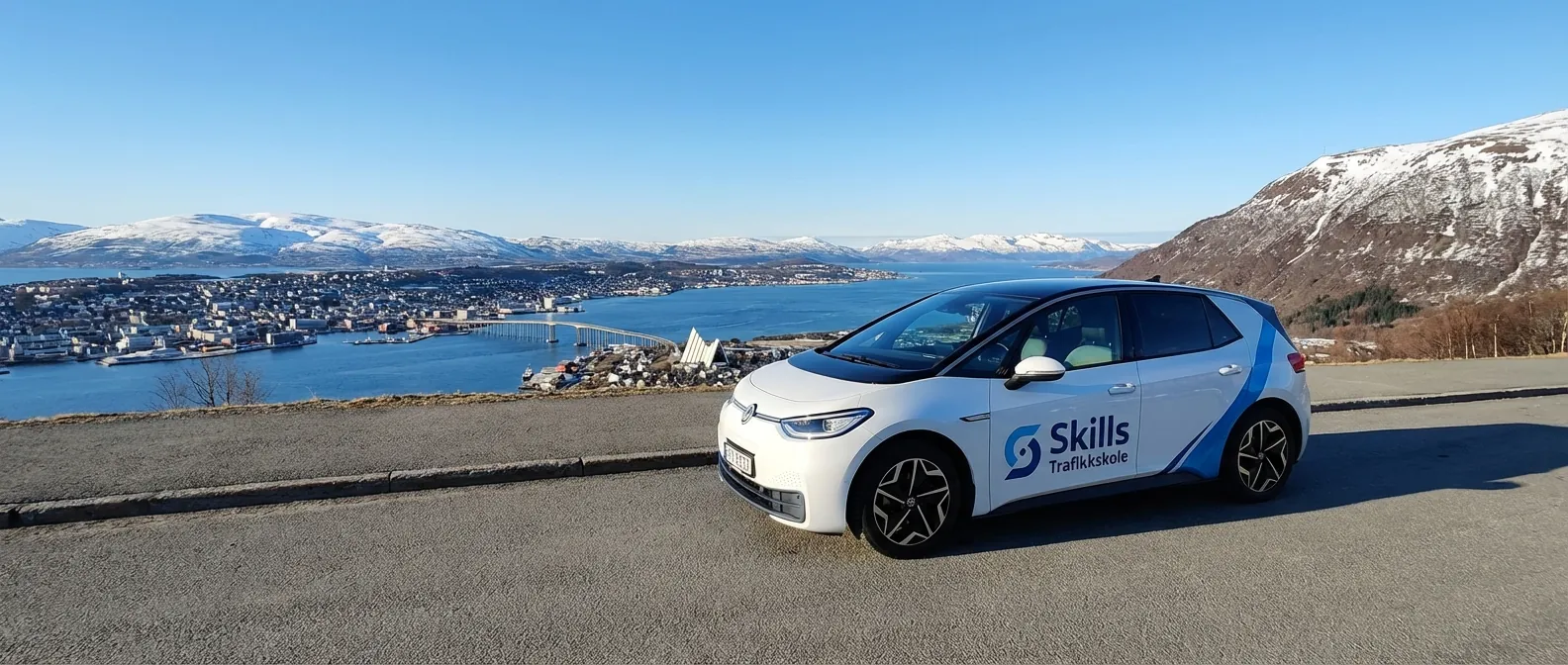 Et oversiktsbilde av Tromsø by med en av Skills Trafikkskoles biler i forgrunnen