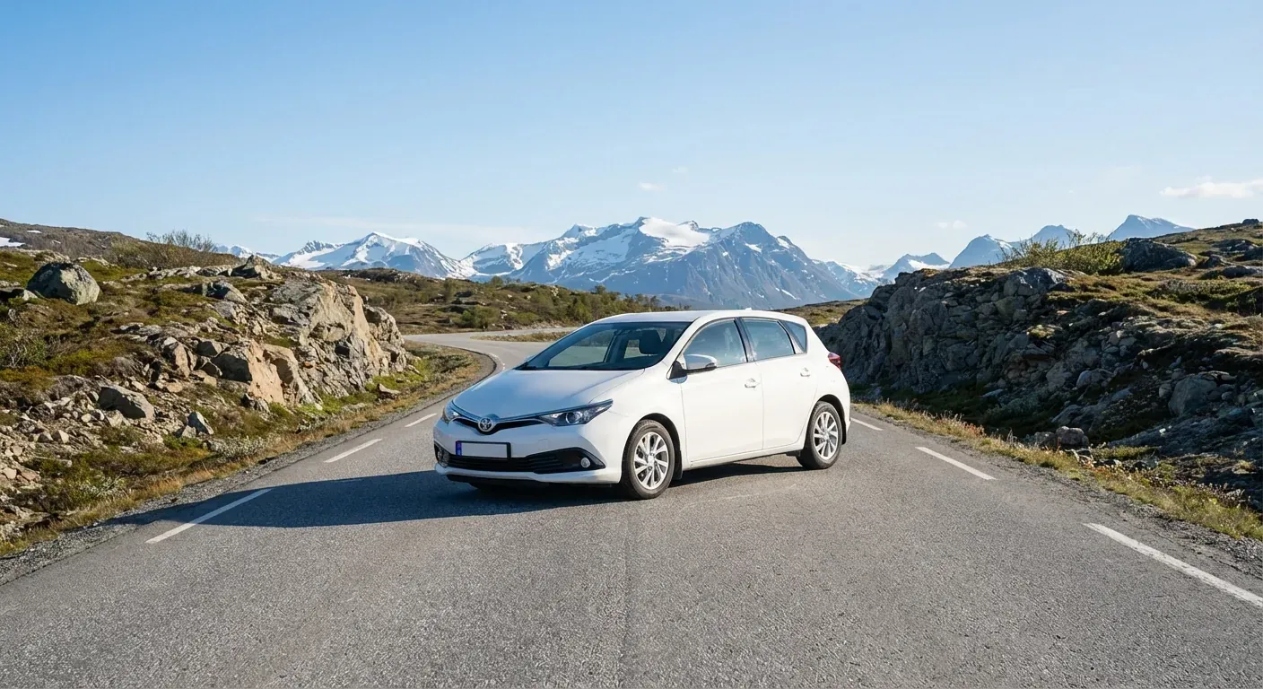 A modern white driving school car parked on a paved street with mountains in the background