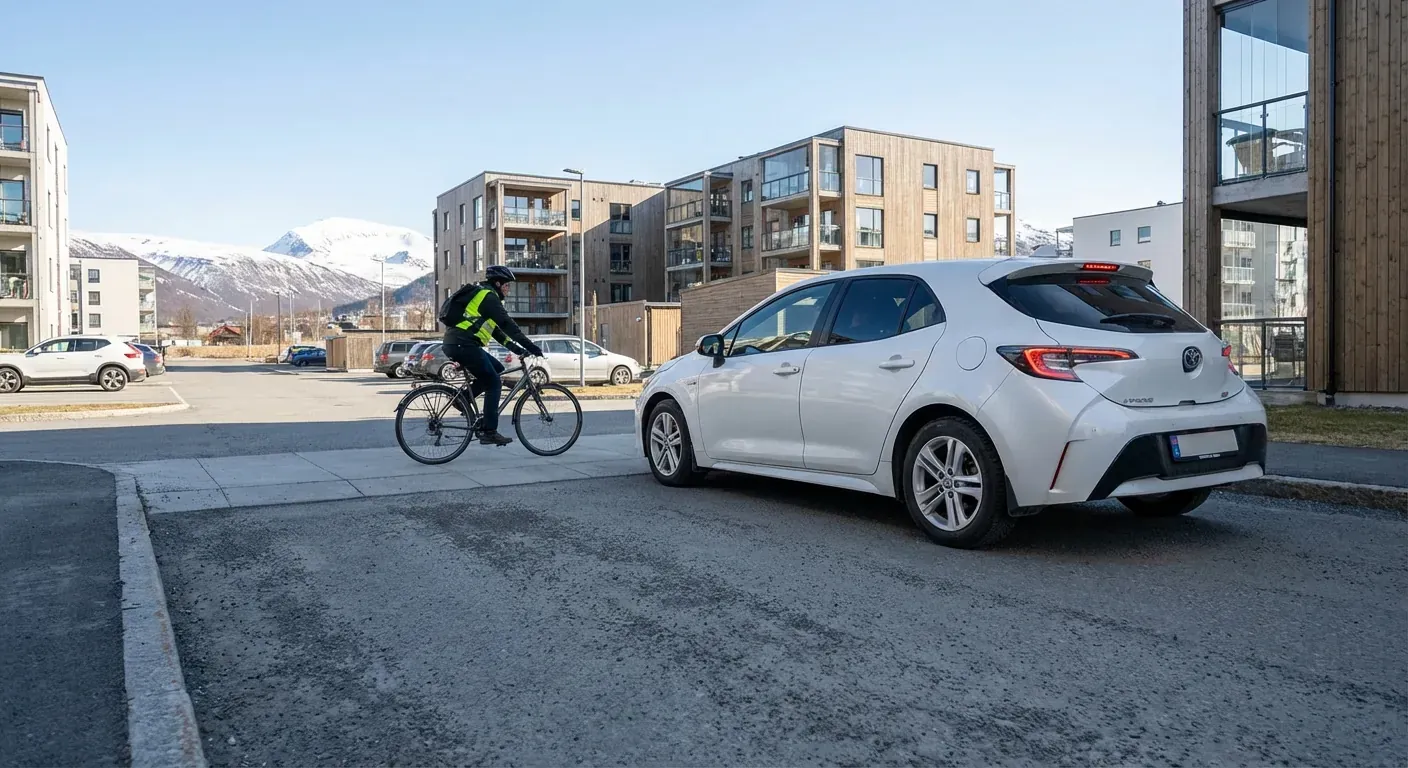 En bil som forsiktig kjører ut fra en parkeringsplass og stopper helt opp for en syklist på fortauet