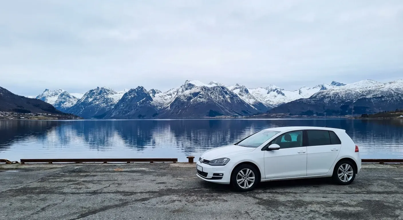 En moderne hvit skolebil parkert ved en kai i Tromsø med fjell i bakgrunnen